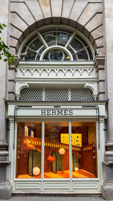 The image depicts the exterior of a building with an ornate stone facade featuring a large arched window at the top, divided into multiple panes by decorative metalwork, and a smaller semi-circular wi